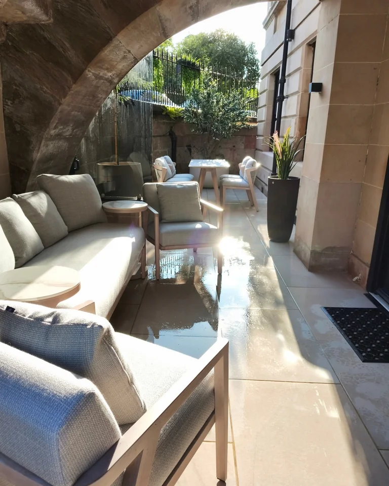 Sheltered terrace with lounge seating, planters and a dining area beneath a stone arch in Central Glasgow